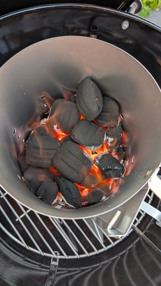 Briquettes catching inside a chimney starter, glowing orange at the bottom