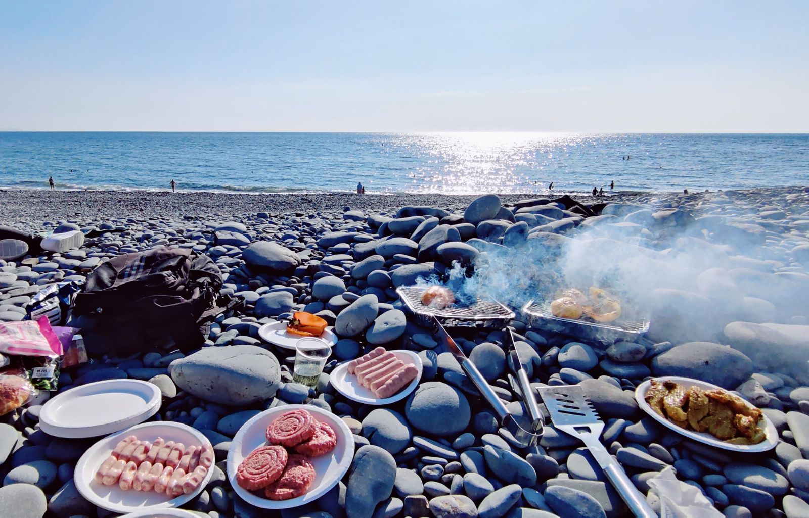BBQ on a pebble beach at Aberystwyth with plates of burgers, sausages and chicken