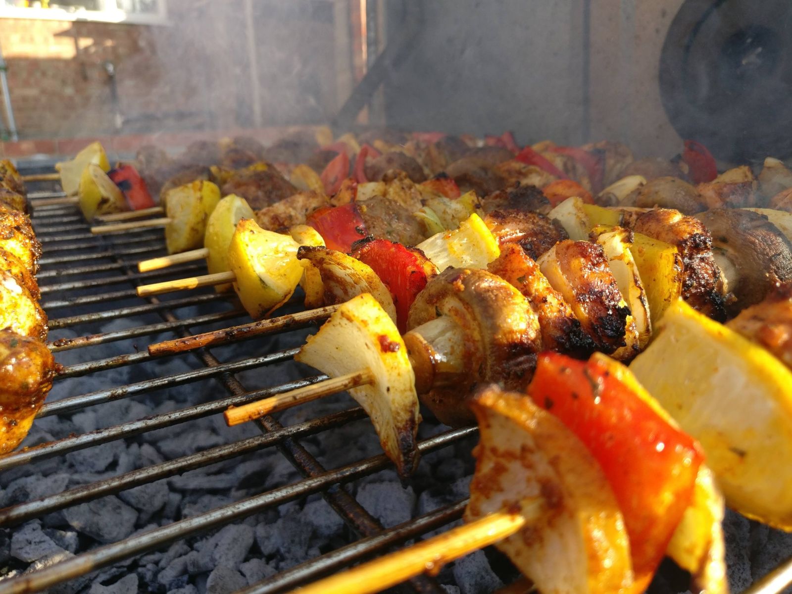 Chicken, pepper, mushroom, onion and lemon skewers on a charcoal BBQ