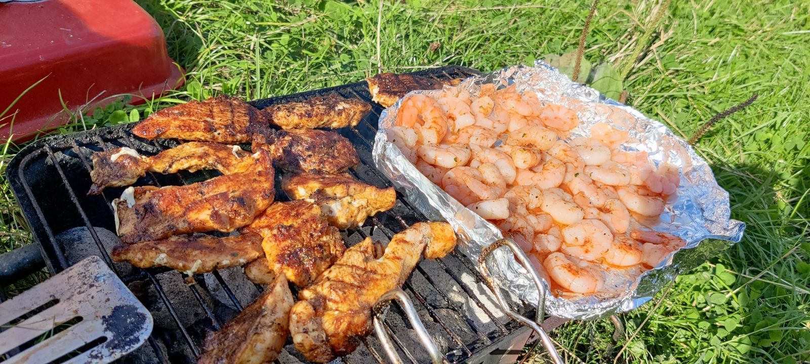 Chicken and prawns cooking on a small grill on a towpath next to a narrowboat