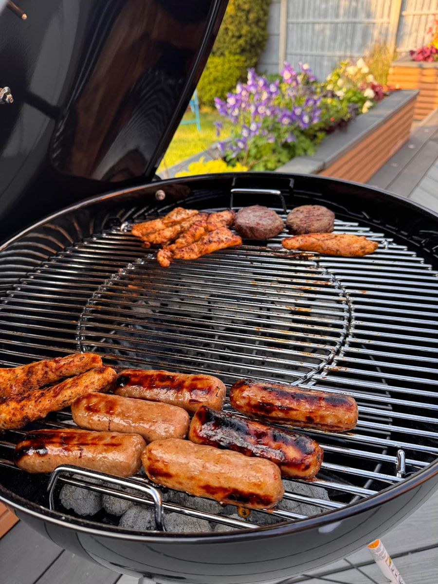 Sausages, chicken strips and burgers on a Weber kettle grill