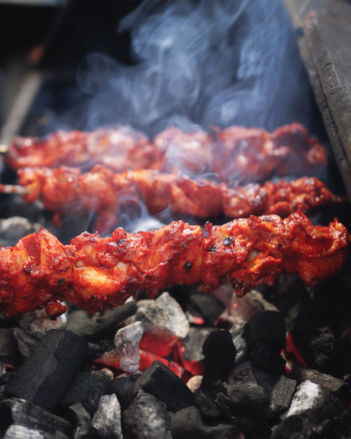 Chicken skewers grilling over glowing charcoal