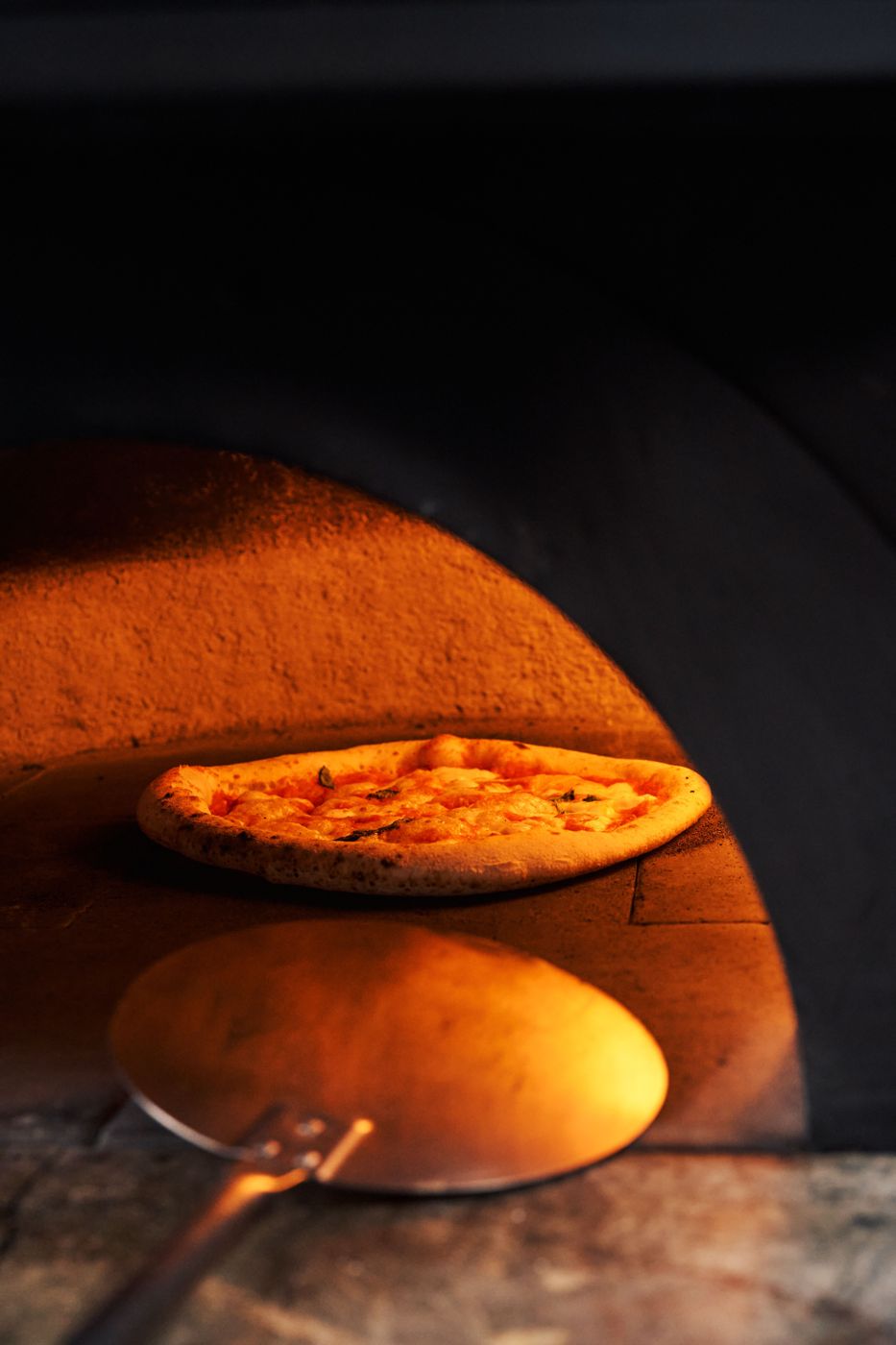 Pizza cooking inside a glowing pizza oven