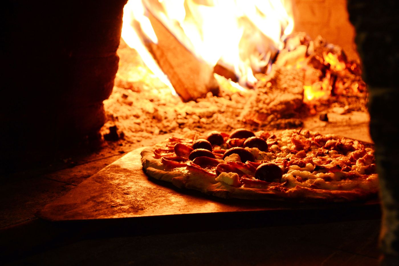 Pepperoni pizza cooking in a wood-fired oven