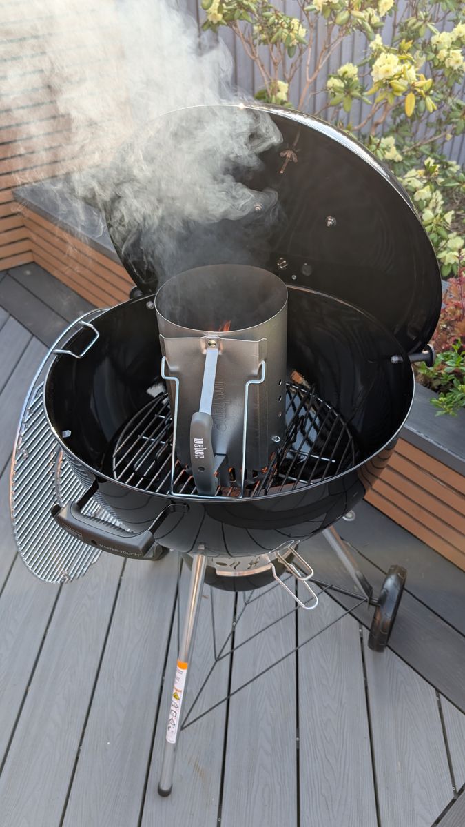 Weber chimney starter smoking as it lights inside a kettle BBQ